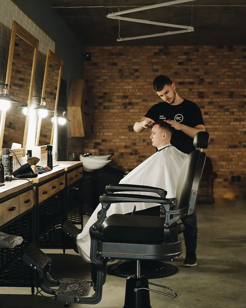 Barbero cortando el pelo a un cliente frente al espejo.