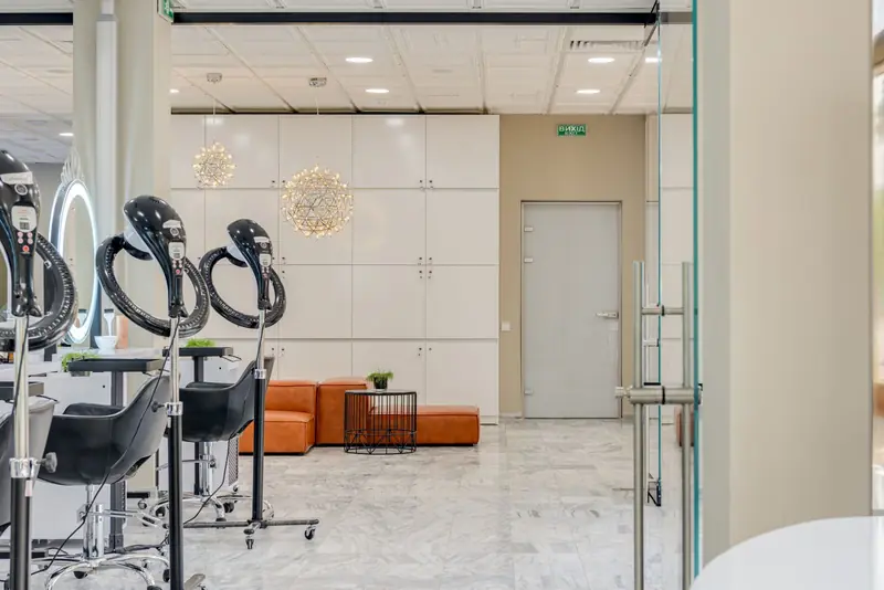 Salón amplio con sillones negros, espejos con luz y piso claro.