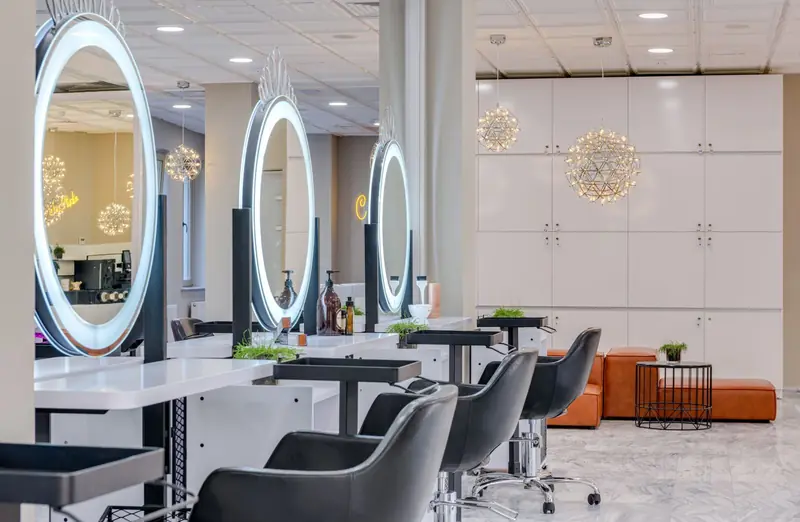 Interior de Peluquería Aurora: sillones, espejos redondos con luz y ambiente luminoso.